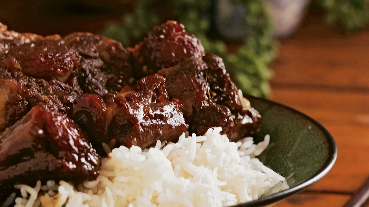 Succulent Beef Stew on Fluffy White Rice in a Green Glassware Dish